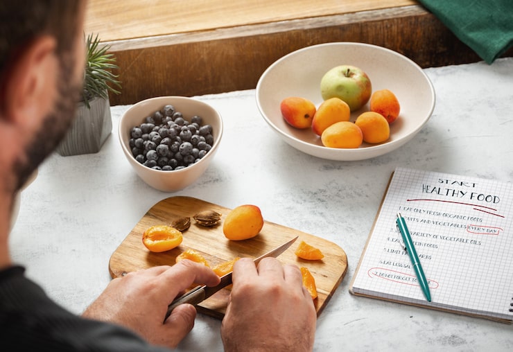 Editorial photograph or illustration of a personalized nutrition consultation in progress — clipboard with handwritten meal plan, fresh produce, supplements, and a warm cup of herbal tea on a wooden table